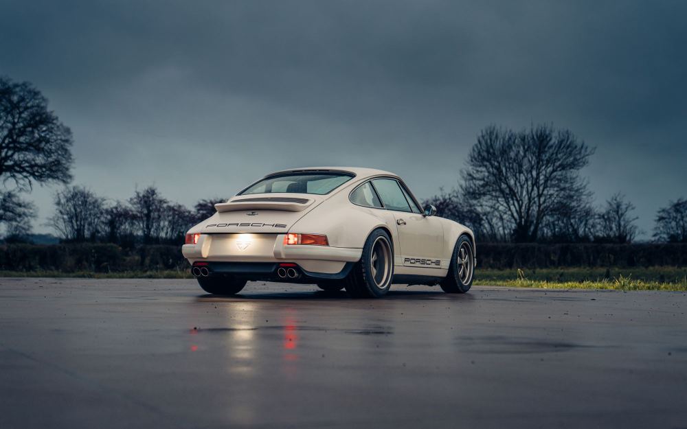 Cream Coupé, a Porsche 911 (964) reimagined by Theon Design: rear three-quarter view on wet tarmac under a stormy sky