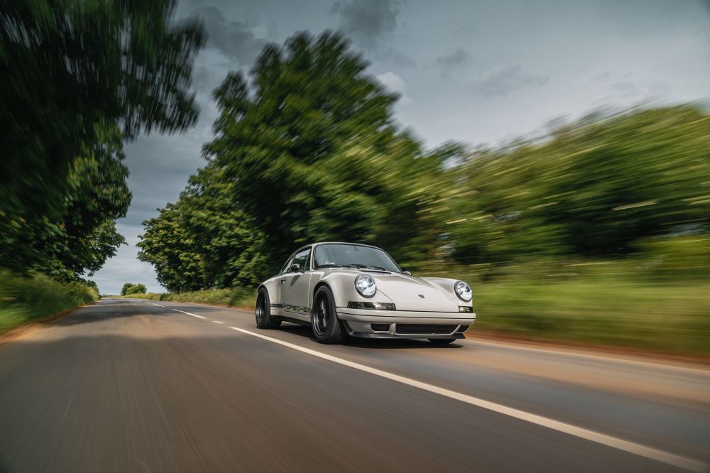 Silver Coupé, a Porsche 911 (964) reimagined by Theon Design: front three-quarter view driving on a tree-lined country road