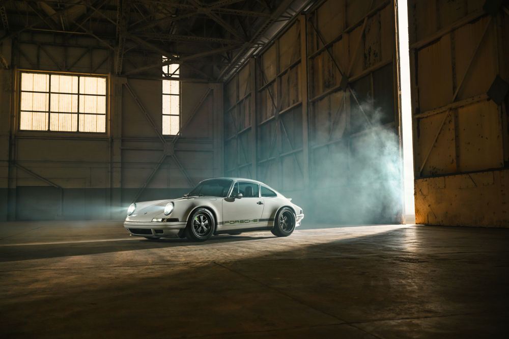 Silver Coupé, a Porsche 911 (964) reimagined by Theon Design: front three-quarter view with headlights on inside a hangar