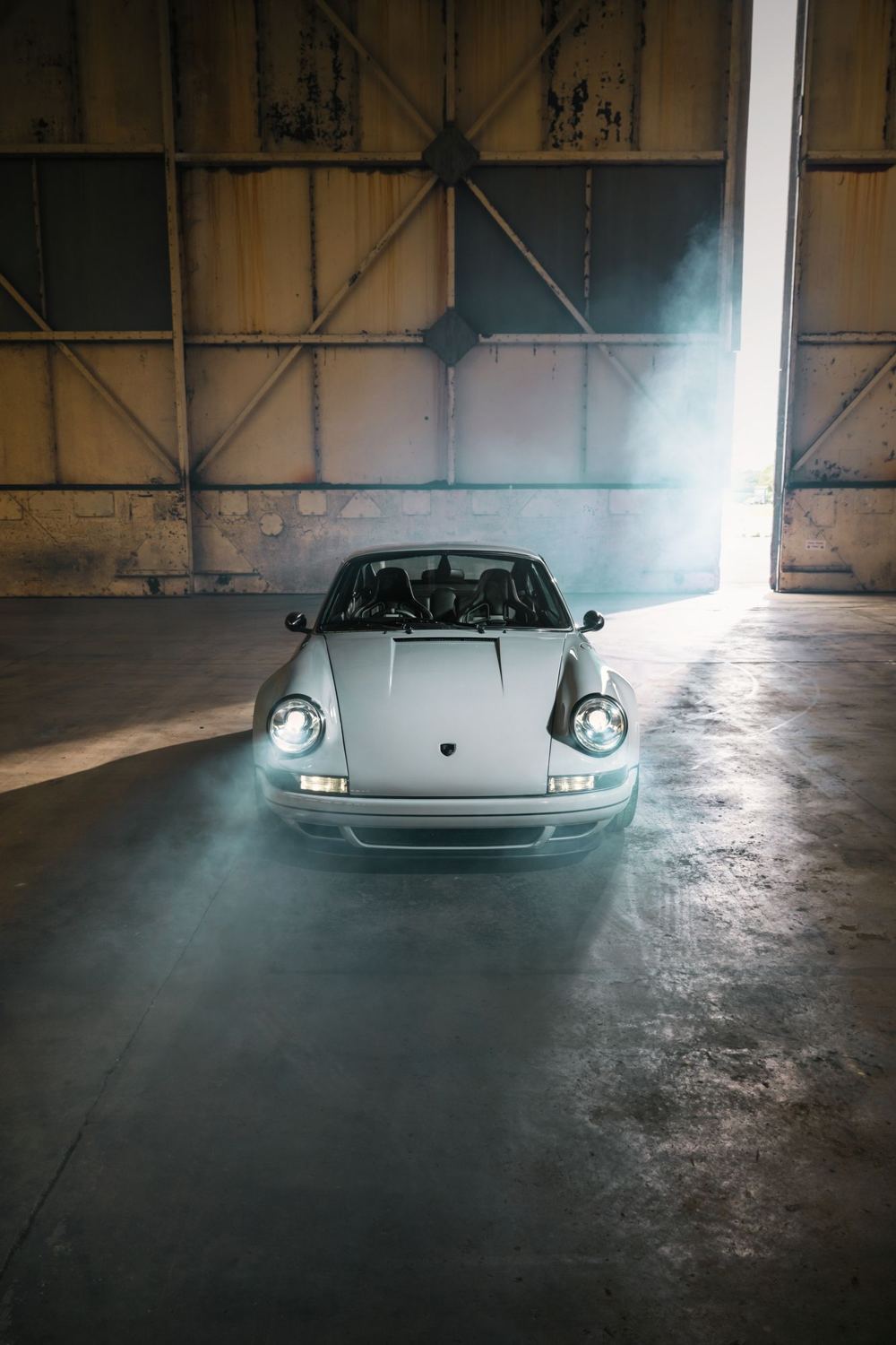 Silver Coupé, a Porsche 911 (964) reimagined by Theon Design: front view in front of the open hangar doors