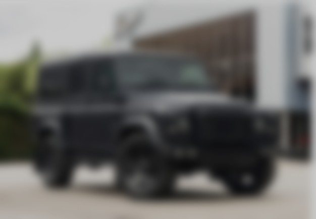 A blurred view of a dark modern SUV parked outside a building