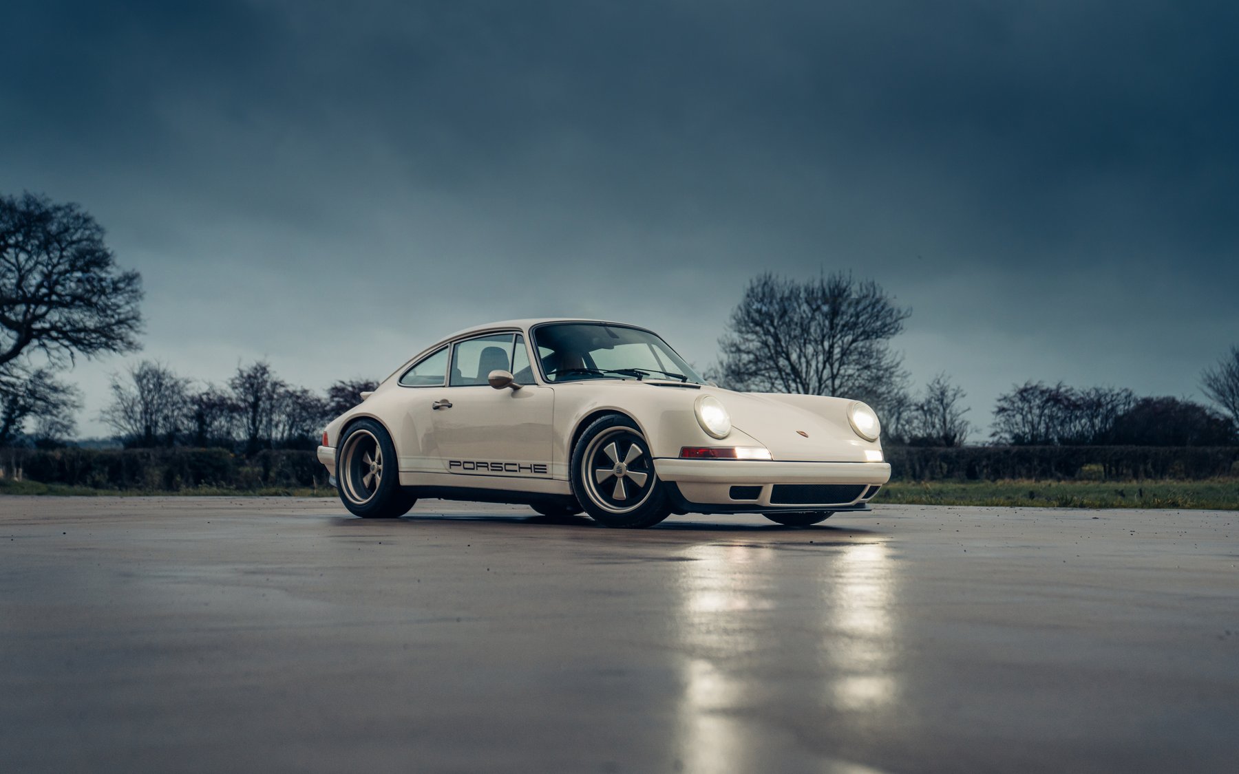 Theon Design bespoke Porsche 911 964 restomod in cream white, low angle moody sky